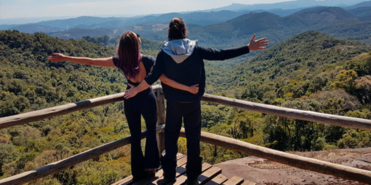 Mulher e homem de costas abraçados olhando para cenário de montanha de Monte Verde Minas